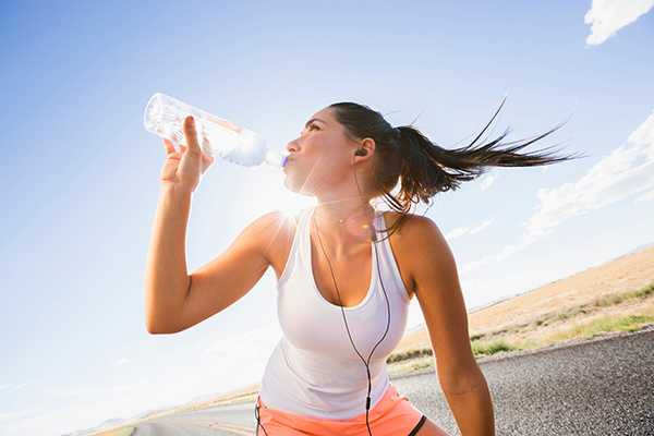 Caucasian runner drinking water bottle on remote road